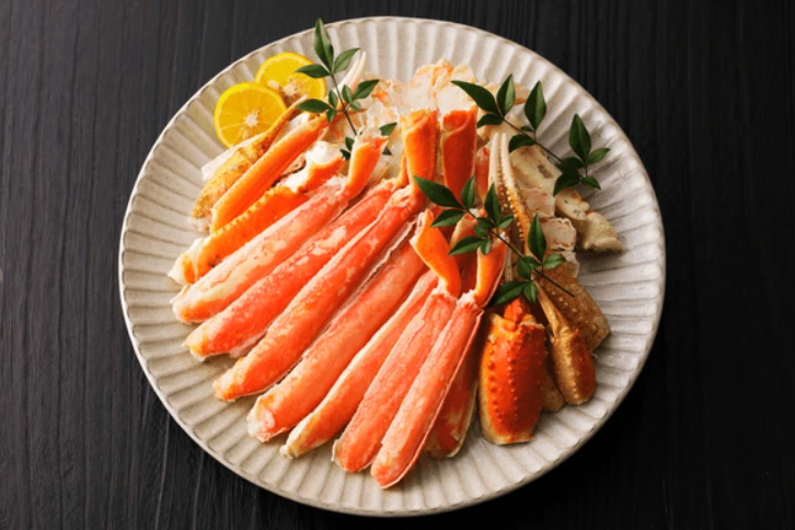 Plated snow crab leg meat dish with lemon wedges, cooked, cracked, hassle free ready to eat.