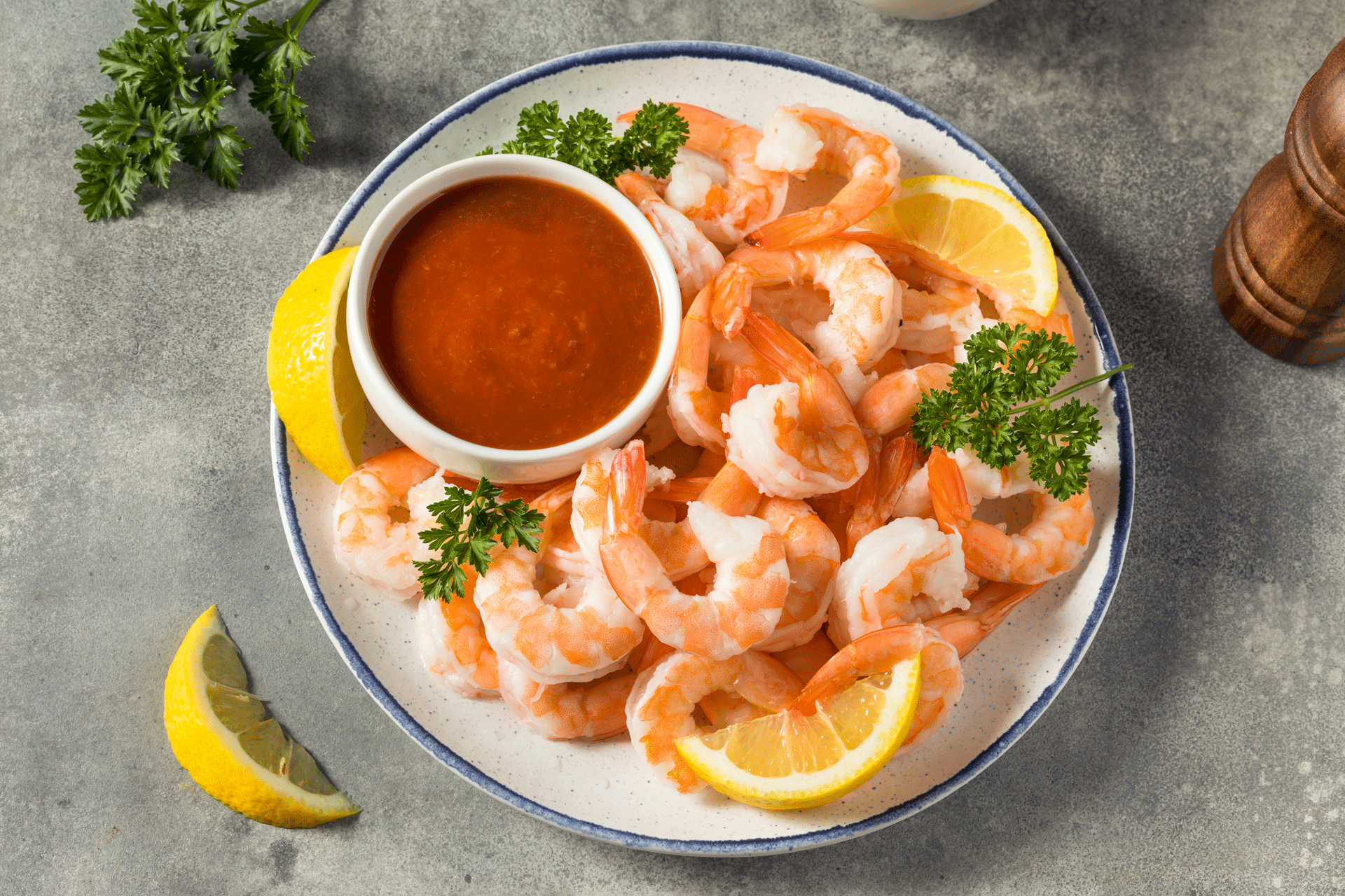 Wild-caught Key West Pink Shrimp, 10/20 count, served on a plate with lemon wedges, cocktail sauce, and a pepper shaker — premium seafood presentation.