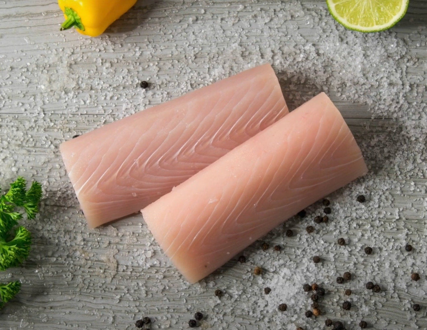 Mahi-Mahi fillets, 6–8 oz wild-caught portions, displayed on table with salt, limes, and ice with firm white flesh — perfect for grilling, blackening, or fish tacos.